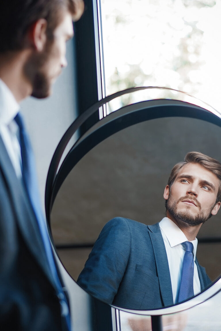 Reflection of handsome young man in full suit standing near the